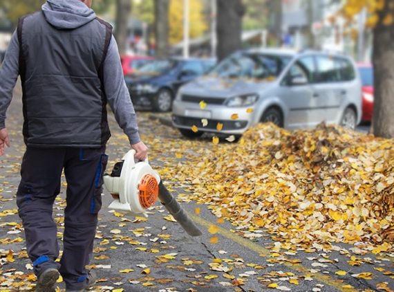 A man is holding an electric leaf blower.