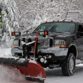 A truck with snow plow in the back of it.