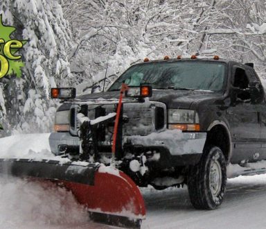 A truck with snow plow in the back of it.