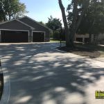 A driveway with two garages and trees in the background.