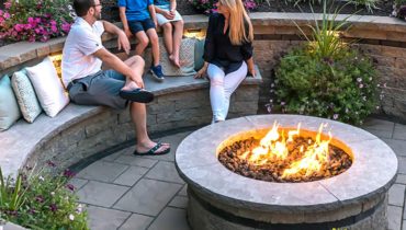 A group of people sitting around an outdoor fire pit.