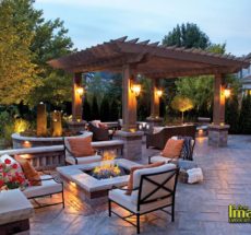 A patio with fire pit and pergola at night.